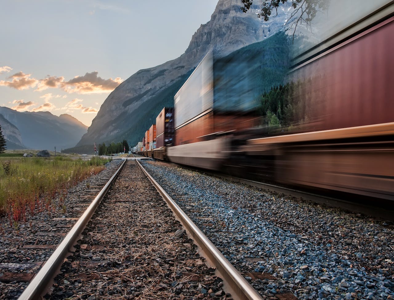 Vivid image of a freight train on tracks beneath majestic mountains in Field, BC.